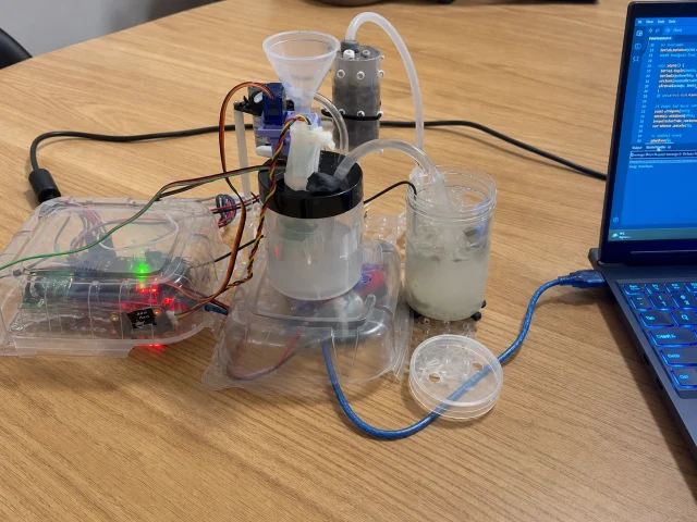 Working water treatment prototype with vessels, tubing, electronics, and a laptop